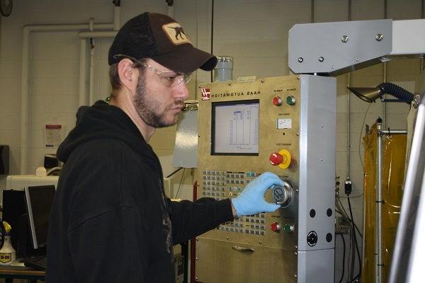穿着黑衬衫和黑帽子的学生在工程实验室使用设备